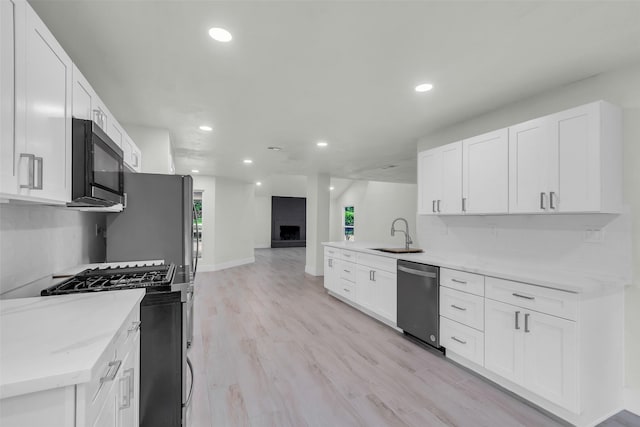 1602 Pine Oak Dr, Conroe, TX 77304 - kitchen with appliances with stainless steel finishes, recessed lighting, a large fireplace, white cabinets, and open floor plan