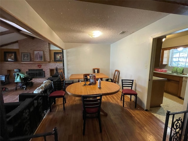 1901 Greenbrook Pkwy, Austin, TX 78723 - dining area featuring light wood-style floors, a textured ceiling, lofted ceiling, and a fireplace