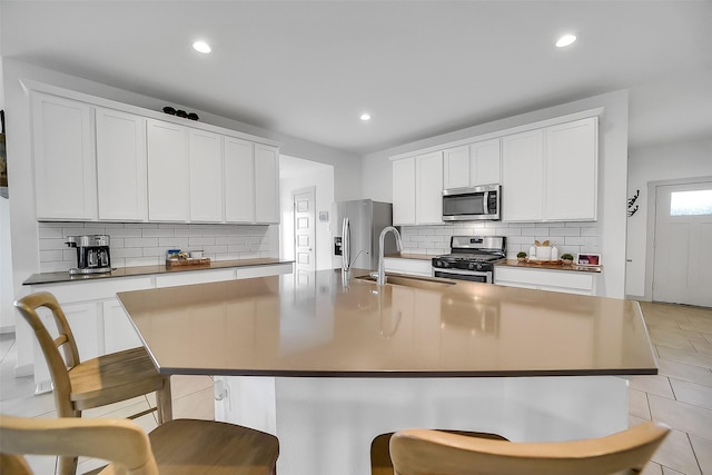 3330 Dagostino Creek Dr, Katy, TX 77494 - kitchen featuring appliances with stainless steel finishes, backsplash, a center island with sink, recessed lighting, and a kitchen breakfast bar