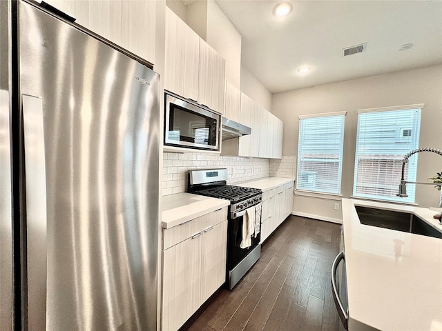 613 Thornton Oaks Ln, Houston, TX 77018 - kitchen with appliances with stainless steel finishes, exhaust hood, light countertops, dark wood-type flooring, and modern cabinets