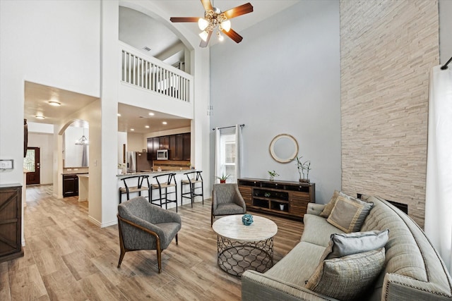 20838 Morgan Knoll Ln, Katy, TX 77449 - living area featuring a high ceiling, ceiling fan, arched walkways, light wood-type flooring, and a fireplace