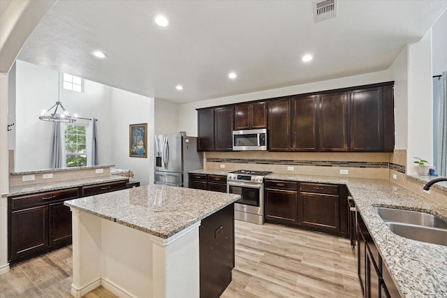 20838 Morgan Knoll Ln, Katy, TX 77449 - kitchen featuring stainless steel appliances, a chandelier, a kitchen island, decorative backsplash, and light wood-type flooring