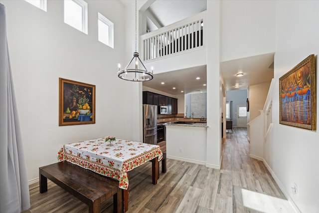20838 Morgan Knoll Ln, Katy, TX 77449 - dining space with a high ceiling, light wood finished floors, a chandelier, and stairs