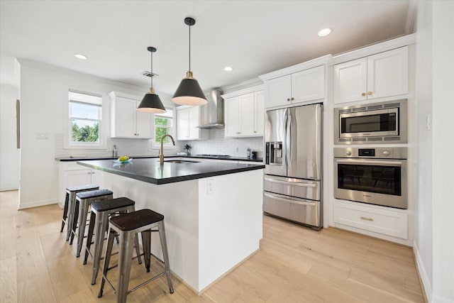 1101 Tabor St, Houston, TX 77009 - kitchen featuring appliances with stainless steel finishes, wall chimney range hood, light wood-style floors, backsplash, and recessed lighting