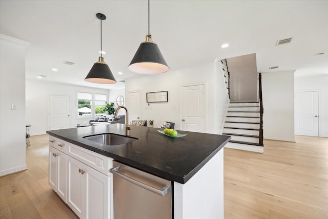 1101 Tabor St, Houston, TX 77009 - kitchen with stainless steel dishwasher, light wood-style flooring, dark countertops, white cabinets, and hanging light fixtures