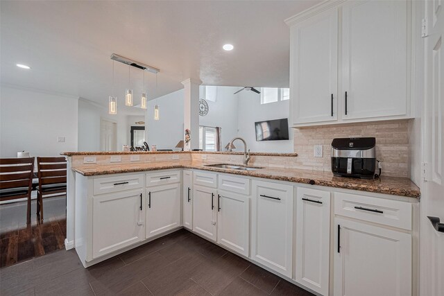 14212 Rocky Briar Ln, Rosharon, TX 77583 - kitchen featuring backsplash, light stone counters, a peninsula, white cabinetry, and pendant lighting