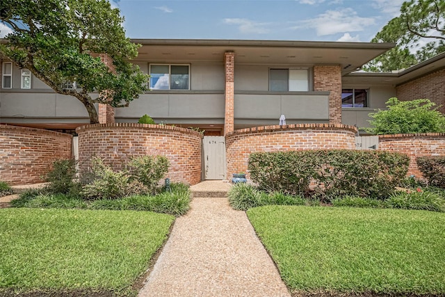 674 S Ripple Creek Dr Unit 674, Houston, TX 77057 - view of front of house with a front yard, stucco siding, and brick siding