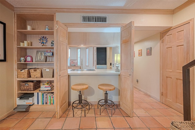 674 S Ripple Creek Dr Unit 674, Houston, TX 77057 - kitchen with ornamental molding, built in features, a kitchen breakfast bar, and light tile patterned floors