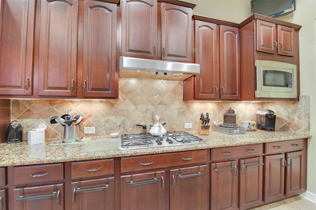 5702 Silverthorn Glen Dr, Spring, TX 77379 - kitchen with stainless steel appliances, under cabinet range hood, light stone countertops, and tasteful backsplash