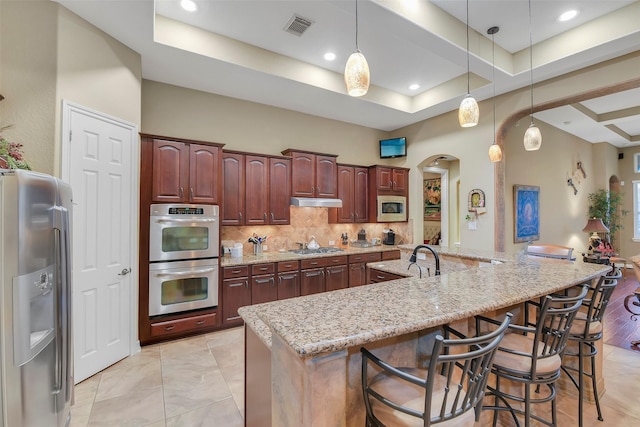 5702 Silverthorn Glen Dr, Spring, TX 77379 - kitchen with appliances with stainless steel finishes, arched walkways, a breakfast bar area, decorative backsplash, and decorative light fixtures