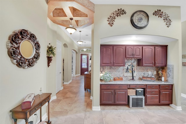 5702 Silverthorn Glen Dr, Spring, TX 77379 - kitchen with arched walkways, backsplash, light stone counters, dark brown cabinets, and light tile patterned floors