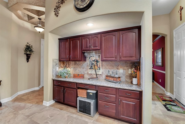 5702 Silverthorn Glen Dr, Spring, TX 77379 - kitchen featuring backsplash, arched walkways, light stone countertops, dark brown cabinets, and light tile patterned floors
