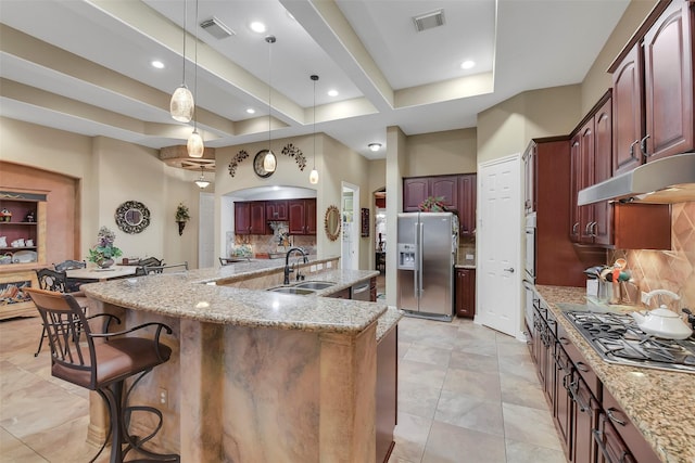 5702 Silverthorn Glen Dr, Spring, TX 77379 - kitchen with appliances with stainless steel finishes, backsplash, a large island, under cabinet range hood, and reddish brown cabinets