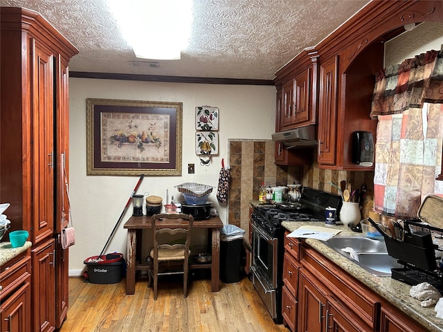 1506 Cordell St, Houston, TX 77009 - kitchen featuring stainless steel gas stove, under cabinet range hood, light wood-style floors, a textured ceiling, and decorative backsplash