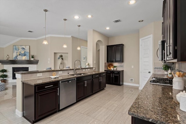 18135 Berry Garden Ln, Spring, TX 77379 - kitchen with appliances with stainless steel finishes, decorative backsplash, dark stone countertops, arched walkways, and a fireplace