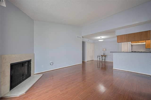 3100 Jeanetta St Unit 1104, Houston, TX 77063 - unfurnished living room featuring wood finished floors, a fireplace with raised hearth, and a textured ceiling