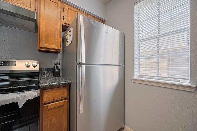 3100 Jeanetta St Unit 1104, Houston, TX 77063 - kitchen featuring appliances with stainless steel finishes, brown cabinetry, and dark stone countertops