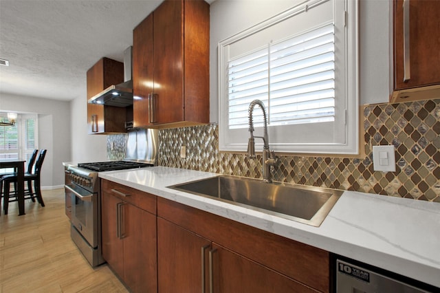 15815 Baytree Dr, Houston, TX 77070 - kitchen with high end stainless steel range, a textured ceiling, decorative backsplash, light wood-type flooring, and wall chimney exhaust hood