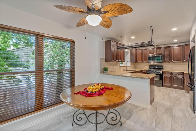 6 Sylvan Forest Dr, The Woodlands, TX 77381 - kitchen featuring stainless steel microwave, gas stove, backsplash, a peninsula, and light stone countertops
