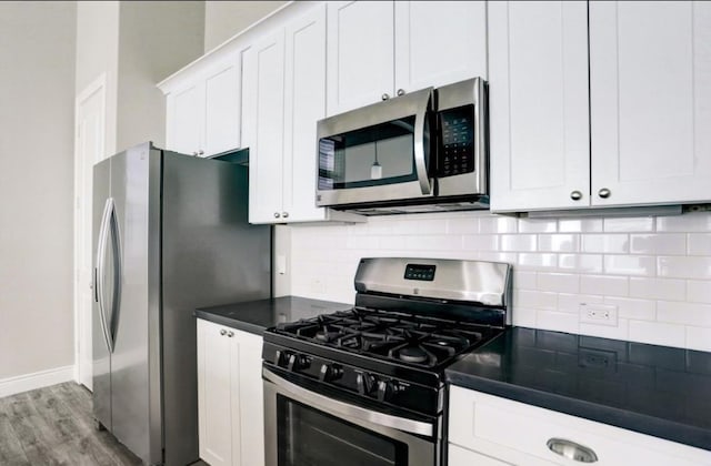 8907 Spring Knoll Forest Dr, Houston, TX 77080 - kitchen featuring stainless steel appliances, light wood-style flooring, backsplash, and dark countertops
