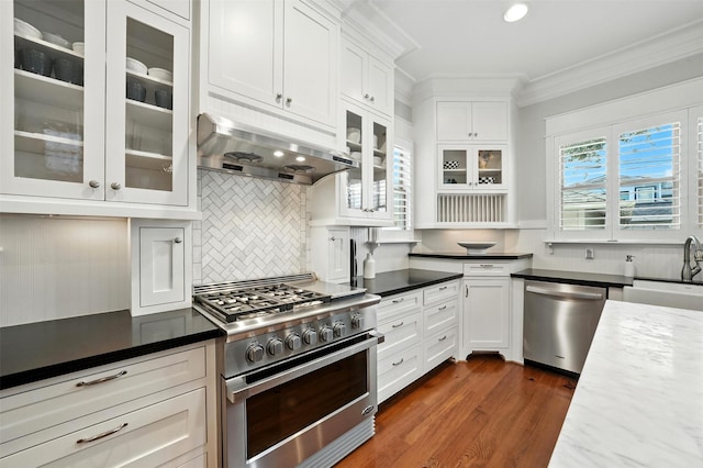 829 Ralfallen St, Houston, TX 77008 - kitchen with stainless steel appliances, exhaust hood, ornamental molding, white cabinetry, and decorative backsplash
