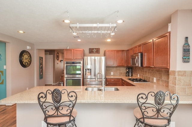 22218 Woodseem Ct, Katy, TX 77449 - kitchen featuring appliances with stainless steel finishes, a breakfast bar, a peninsula, decorative backsplash, and recessed lighting