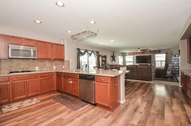 22218 Woodseem Ct, Katy, TX 77449 - kitchen featuring appliances with stainless steel finishes, a peninsula, light countertops, healthy amount of natural light, and recessed lighting