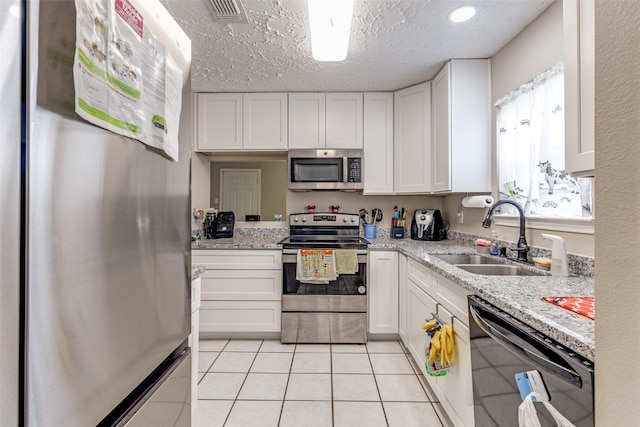 7307 Sunlight Ln, Houston, TX 77095 - kitchen featuring stainless steel appliances, white cabinetry, light tile patterned flooring, and a textured ceiling
