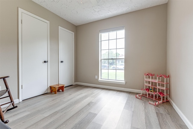 7307 Sunlight Ln, Houston, TX 77095 - game room with light wood-style floors and a textured ceiling