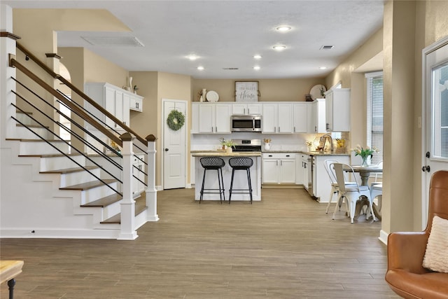 18219 Water Mill Dr, Cypress, TX 77429 - kitchen featuring appliances with stainless steel finishes, a kitchen island, recessed lighting, white cabinetry, and light wood-style flooring
