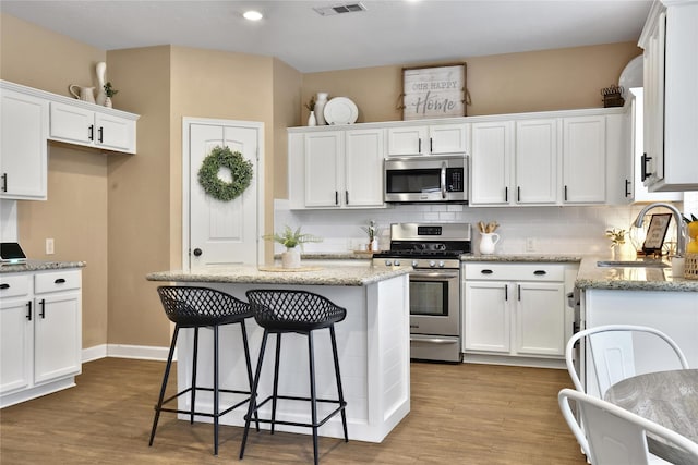 18219 Water Mill Dr, Cypress, TX 77429 - kitchen with stainless steel appliances, white cabinets, wood finished floors, decorative backsplash, and recessed lighting
