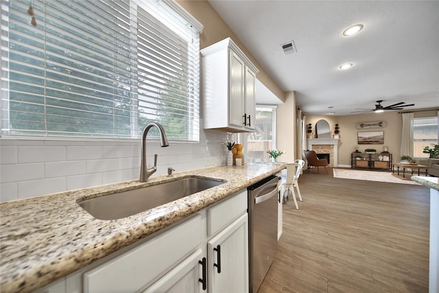 18219 Water Mill Dr, Cypress, TX 77429 - kitchen featuring dishwasher, backsplash, ceiling fan, a fireplace, and white cabinets