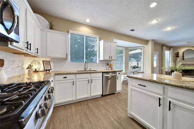 18219 Water Mill Dr, Cypress, TX 77429 - kitchen with appliances with stainless steel finishes, recessed lighting, white cabinets, light wood-style flooring, and backsplash