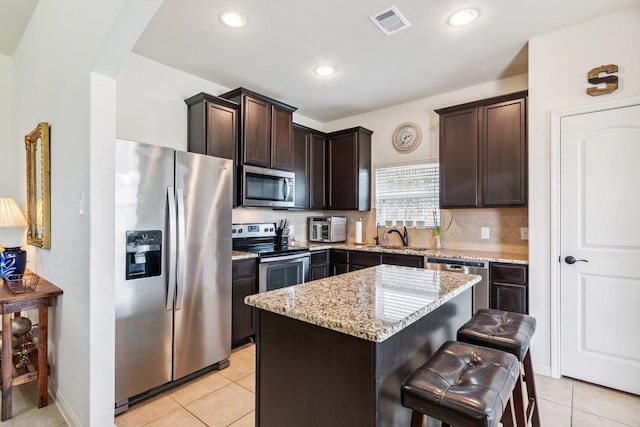 21015 Echo Manor Dr, Hockley, TX 77447 - kitchen with stainless steel appliances, arched walkways, dark brown cabinets, light stone countertops, and a center island
