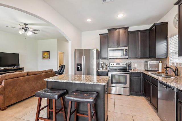 21015 Echo Manor Dr, Hockley, TX 77447 - kitchen featuring stainless steel appliances, open floor plan, light stone countertops, a ceiling fan, and light tile patterned flooring