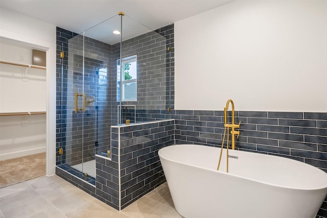 882 Prosper St, Houston, TX 77088 - full bathroom featuring a stall shower, a walk in closet, a soaking tub, tile walls, and tile patterned floors