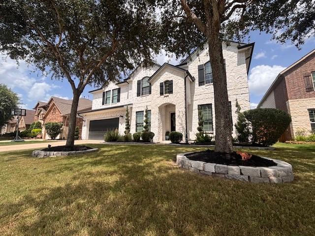 10214 Texas Sage Way, Cypress, TX 77433 - french country style house featuring a front lawn, a garage, stone siding, and driveway