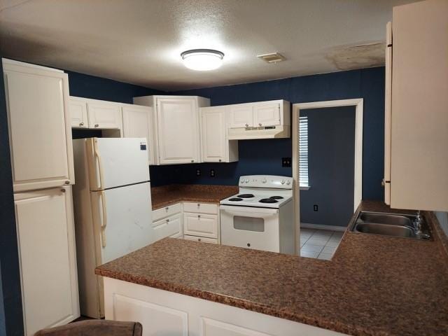 380 Rae Ann Blvd, Livingston, TX 77351 - kitchen with white appliances, under cabinet range hood, dark countertops, white cabinetry, and a peninsula