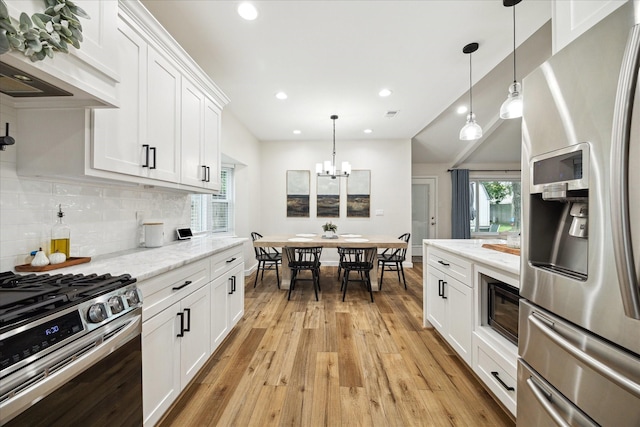 16217 Singapore Ln, Jersey Village, TX 77040 - kitchen with appliances with stainless steel finishes, light wood finished floors, a chandelier, white cabinets, and decorative backsplash