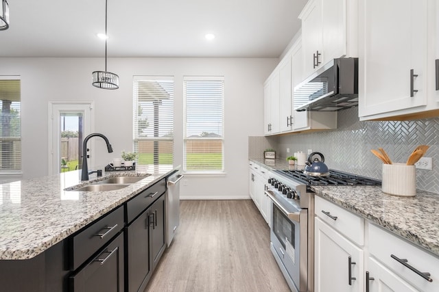 4118 Palmer Meadow Ct, Katy, TX 77494 - kitchen with appliances with stainless steel finishes, light wood-style floors, tasteful backsplash, white cabinetry, and an island with sink