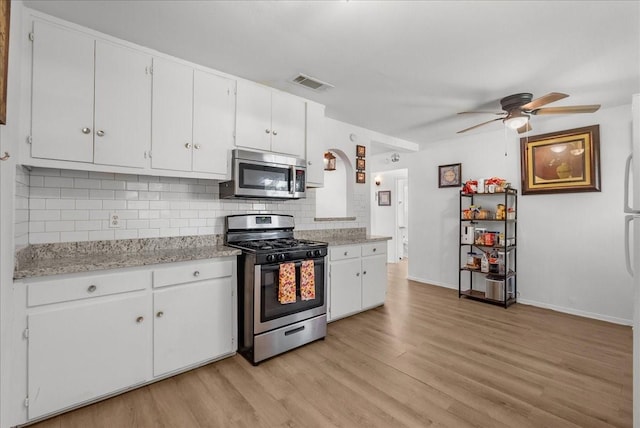 1312 22nd St N, Texas City, TX 77590 - kitchen featuring stainless steel appliances, decorative backsplash, light wood-style flooring, white cabinets, and a ceiling fan