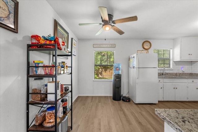 1312 22nd St N, Texas City, TX 77590 - kitchen with freestanding refrigerator, light wood-style flooring, white cabinetry, decorative backsplash, and a ceiling fan
