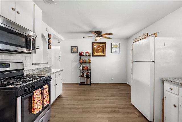 1312 22nd St N, Texas City, TX 77590 - kitchen featuring range with gas stovetop, freestanding refrigerator, stainless steel microwave, a ceiling fan, and white cabinets
