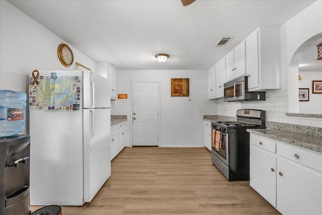 1312 22nd St N, Texas City, TX 77590 - kitchen featuring stainless steel appliances, arched walkways, tasteful backsplash, white cabinets, and light wood finished floors
