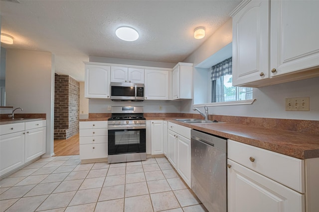 22522 Round Valley Dr, Katy, TX 77450 - kitchen with stainless steel appliances, light tile patterned flooring, white cabinetry, and a textured ceiling