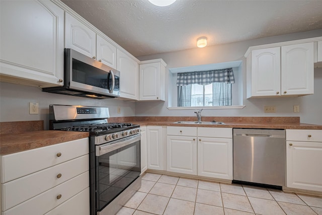 22522 Round Valley Dr, Katy, TX 77450 - kitchen with appliances with stainless steel finishes, light tile patterned floors, white cabinetry, and a textured ceiling