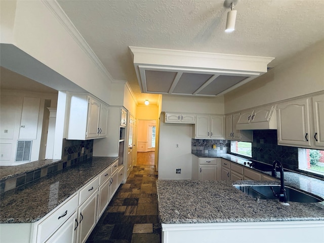 2147 Heather Green Dr, Houston, TX 77062 - kitchen featuring a peninsula, dark stone countertops, decorative backsplash, a textured ceiling, and crown molding