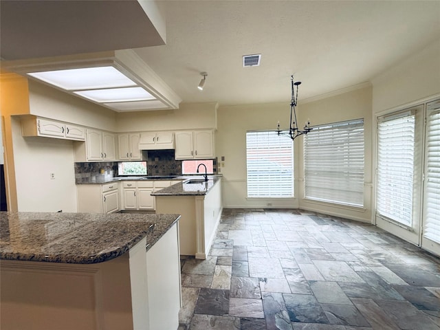 2147 Heather Green Dr, Houston, TX 77062 - kitchen featuring stone tile flooring, healthy amount of natural light, a peninsula, dark stone counters, and crown molding