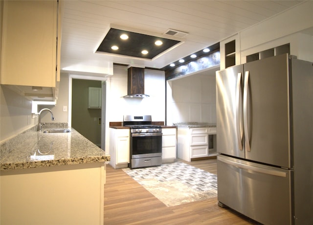 522 Oyster Creek Dr, Richwood, TX 77531 - kitchen featuring appliances with stainless steel finishes, wall chimney exhaust hood, light wood-style flooring, white cabinetry, and light stone counters
