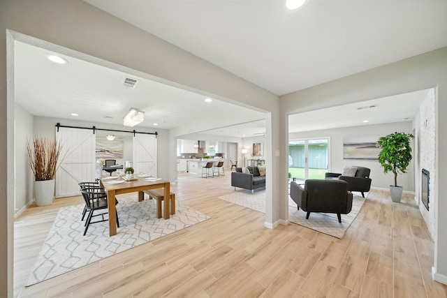 4003 Mischire Dr, Houston, TX 77025 - dining room with a barn door, light wood-style floors, recessed lighting, and a glass covered fireplace